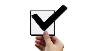 Dłoń trzyma kwadrat z zaznaczonym ptaszkiem. To znak, że input checkbox checked.