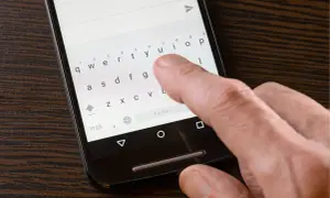Dłoń pisze na klawiaturze telefonu, ale polskie znaki nie działają. Widoczny przycisk "Polski" sugeruje próbę zmiany języka.