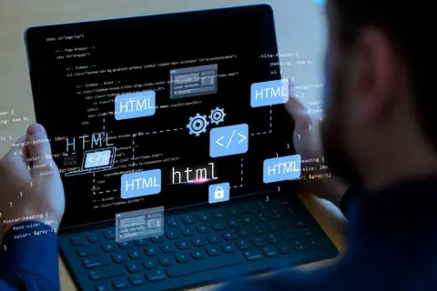 Programista pracuje nad stroną internetową, widoczny kod HTML i ikony symbolizujące tworzenie stron.