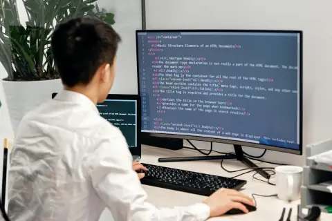 Programista uczy się podstaw Docker, pisząc kod HTML na monitorze.