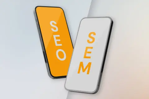 Dwa telefony: jeden z napisem SEO na pomarańczowym tle, drugi z napisem SEM na białym. Porównanie strategii SEO vs SEM.