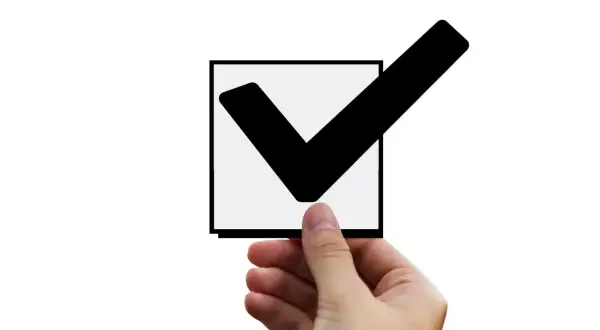 Dłoń trzyma kwadrat z zaznaczonym ptaszkiem. To znak, że input checkbox checked.