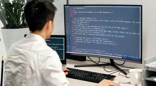 Programista uczy się podstaw Docker, pisząc kod HTML na monitorze.