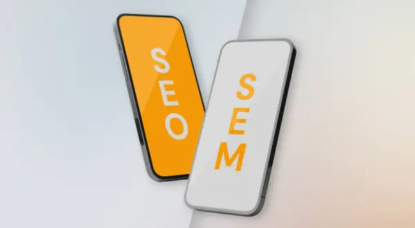 Dwa telefony: jeden z napisem SEO na pomarańczowym tle, drugi z napisem SEM na białym. Porównanie strategii SEO vs SEM.