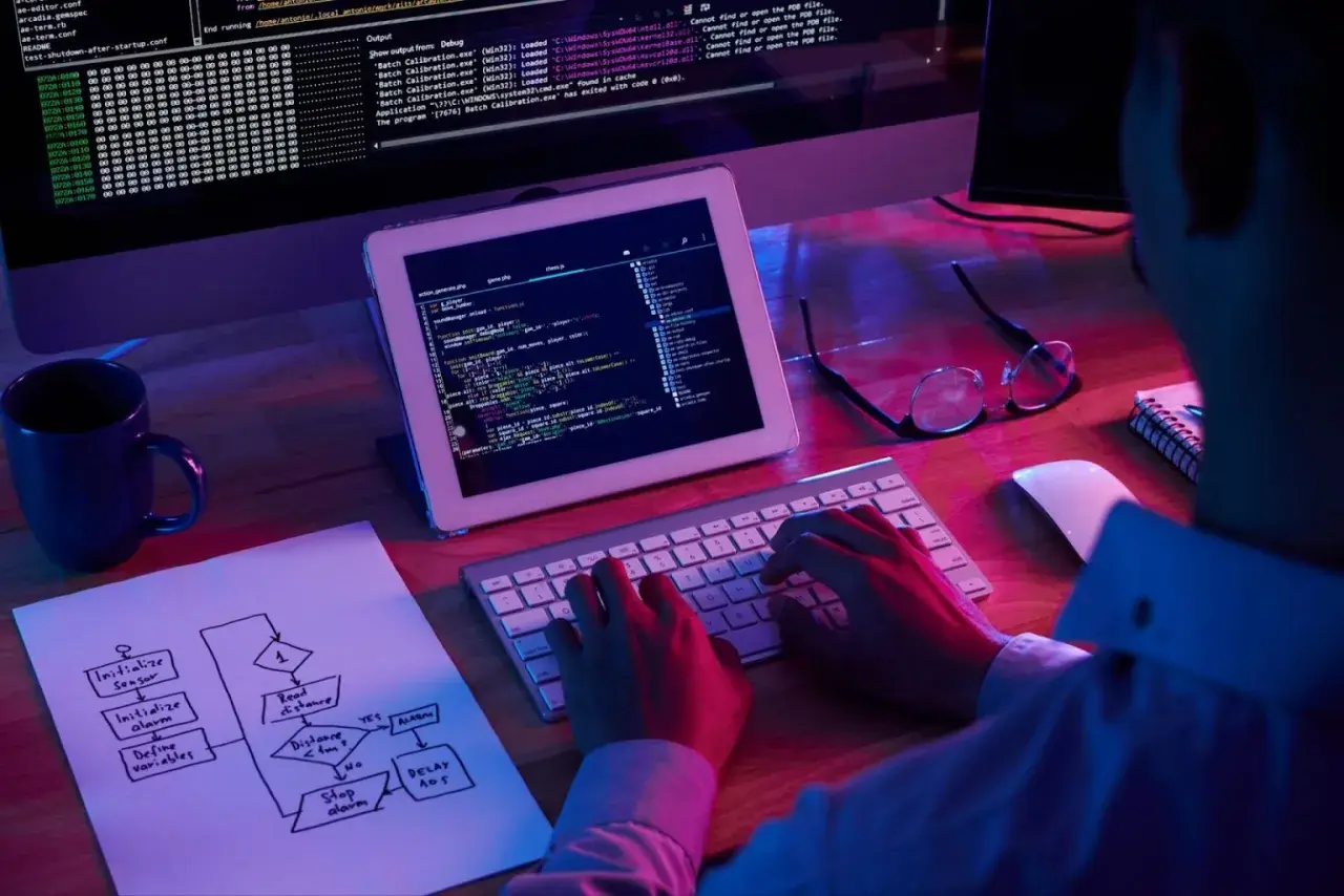 Programista pracuje nad kodem, na ekranie widać tekst i schemat blokowy. H1 html.