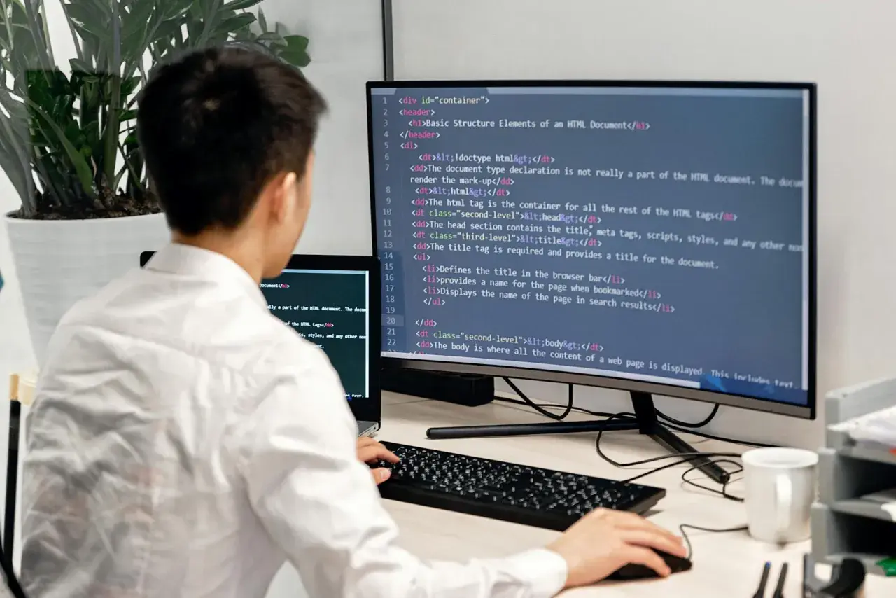 Programista uczy się podstaw Docker, pisząc kod HTML na monitorze.