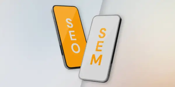 Dwa telefony: jeden z napisem SEO na pomarańczowym tle, drugi z napisem SEM na białym. Porównanie strategii SEO vs SEM.